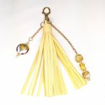 Bijou de sac, pompon cuir coloris jaune avec perles en verre filé et cloisonné.